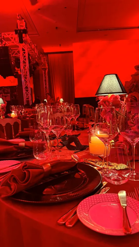 Red table settings, candles and glassware at a masquerade birthday dinner in Dubai