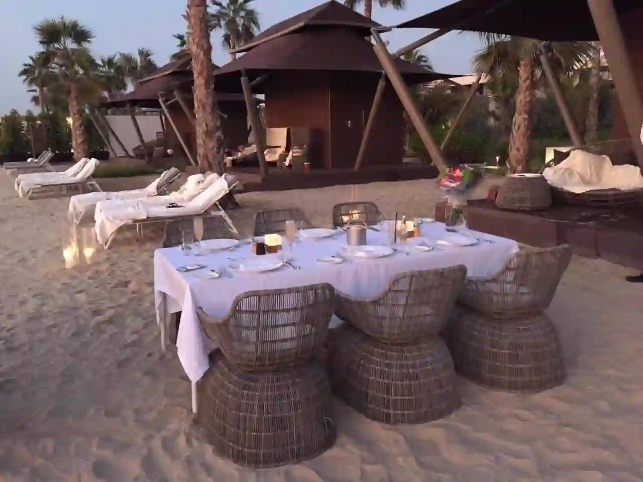 Private dinner table set on a Dubai beach at dusk
